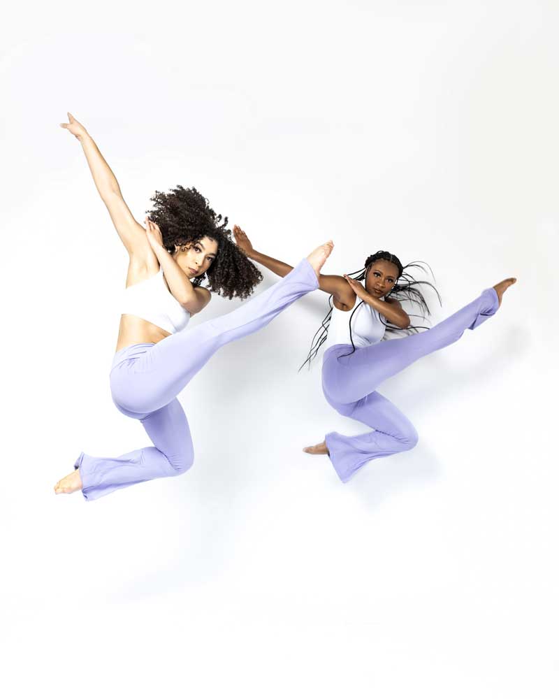 Two Dance ELITE dancers in lavender leaping mid-air